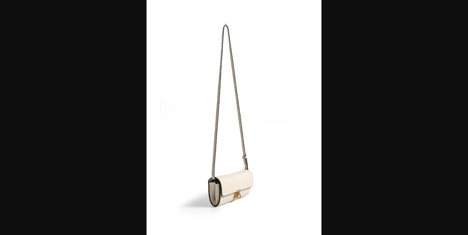 Bob Oré Aria in White leather shown in crossbody configuration — the elongated capsule shape and gold ring lock hardware are clearly visible hanging from the adjustable leather shoulder strap.