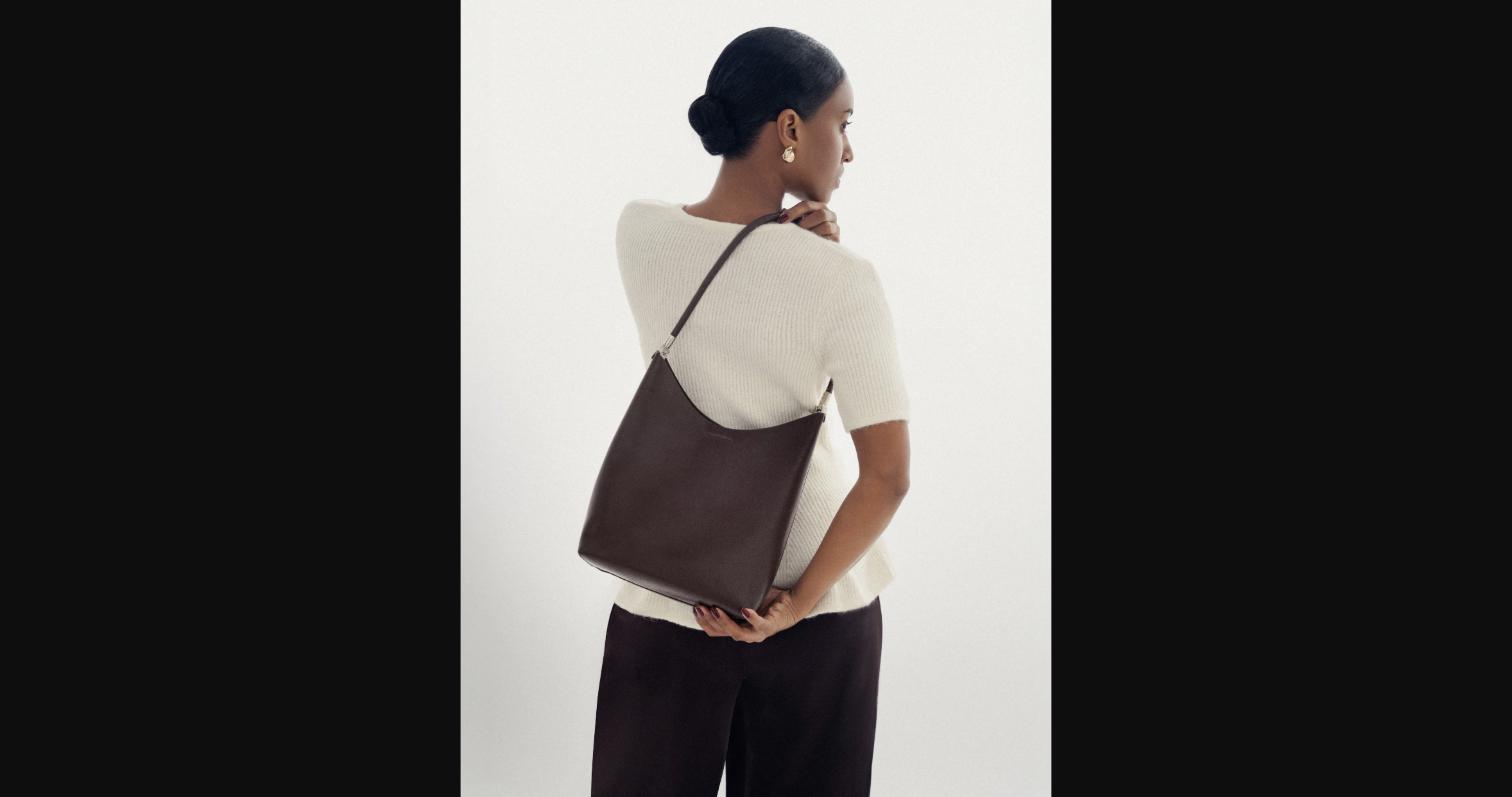 The Eclipse in Chocolate leather worn over one shoulder — the curved silhouette and slim strap drape naturally against the body, shown here with the Bobore signature minimal hardware.