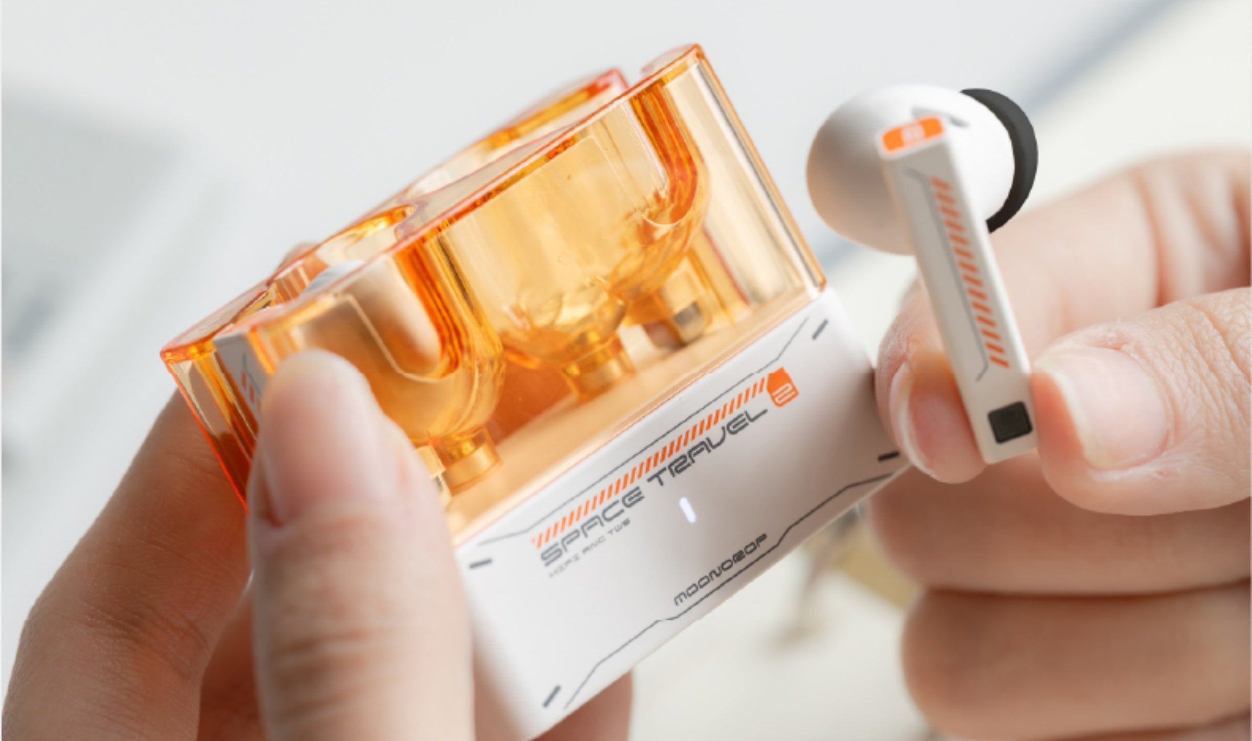 A close-up in-hand shot showing the case's translucent build and the earbud's touch-control stem