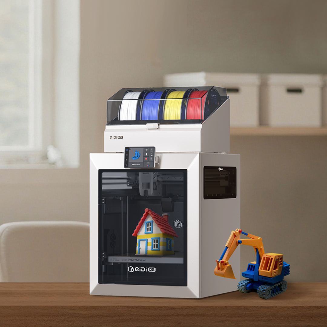 A real desk setup showing the Q2C paired with the optional QIDI Box multi-color unit and a finished multi-color print