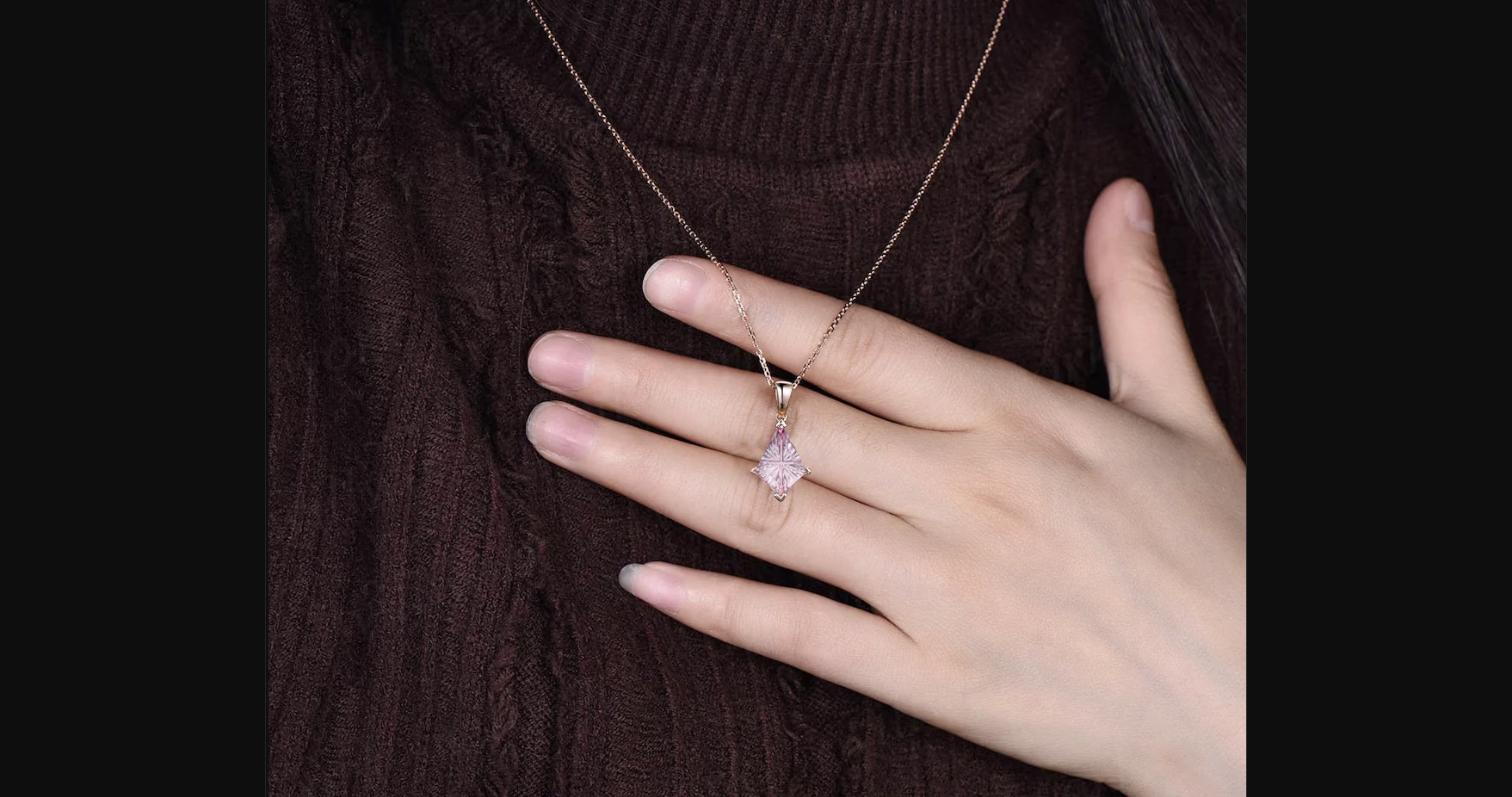The kite fantasy cut padparadscha pendant worn on a rose gold chain — the geometric stone sits close to the neckline and catches light across its fantasy-cut facets.